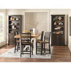 a dining room table and chairs in front of a bookcase filled with vases