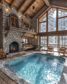 an indoor swimming pool in the middle of a living room with stone fireplace and large windows