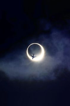 an airplane is flying through the sky with a ring around it's neck and moon in the background