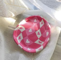 a pink and white plate with hearts on it sitting on a tablecloth covered surface