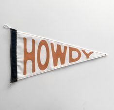 a pennant with the words howdy printed on it hanging from a wall in front of a white background