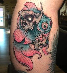 a skull and fish tattoo on the leg of a woman's thigh with pink hair