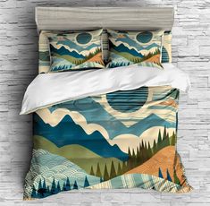 an image of a bed set with mountains and trees on the pillow cover, in front of a brick wall