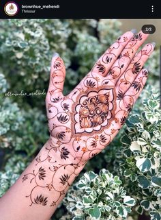 a person's hand with henna on it and flowers in the back ground