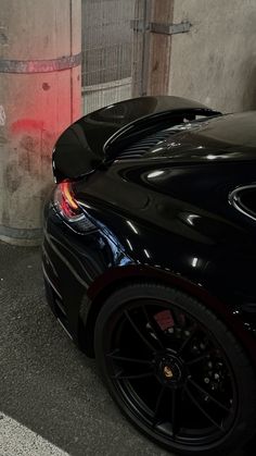 a black sports car parked next to a trash can