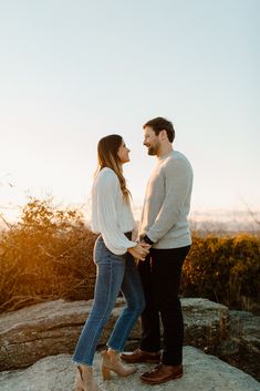 a man and woman standing on top of a rock