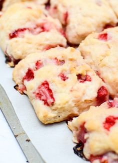 strawberry muffins are sitting on a baking sheet with a knife next to them