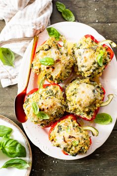 stuffed peppers with cheese and spinach on a white plate next to some basil leaves