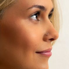 a close up of a person wearing earring on her nose and looking off to the side