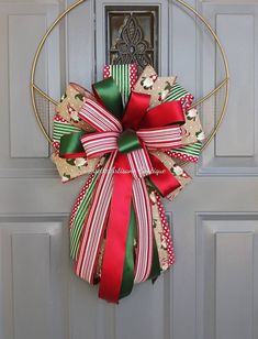 a christmas wreath with red, green and gold ribbons hanging on a metal door frame