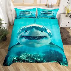 a bed with a shark design on the cover and pillow cases in blue water, next to a plant