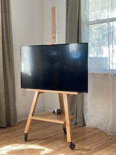 a flat screen tv sitting on top of a wooden stand in front of a window