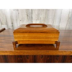 a wooden box sitting on top of a table next to a piece of wood with a handle