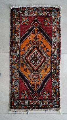 an orange and black rug on the floor with white tiles in the backround