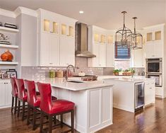 a kitchen with white cabinets and red chairs