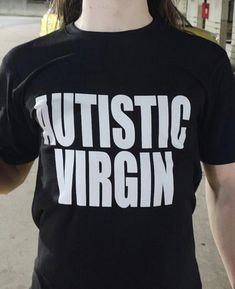 a man with long hair wearing a black shirt that says, autisttic virgin