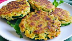 three zucchini fritters on a white plate with green garnish