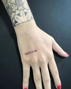 a woman's hand with the word continue tattooed on her left wrist and red nail polish