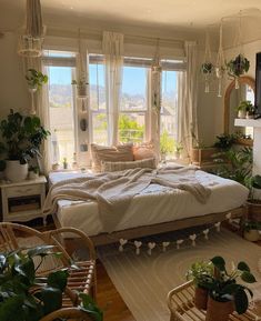 a bed sitting in a bedroom next to a window filled with lots of green plants