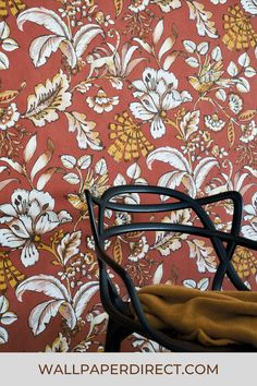 a chair sitting in front of a wallpapered with flowers on it's side