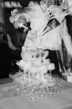 black and white photograph of a man in front of a table with many glasses on it