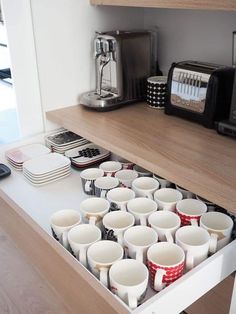 a drawer full of coffee cups on a kitchen counter