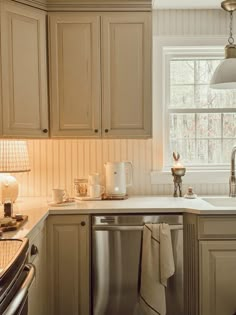 a kitchen with beige cabinets and white counter tops, an open dishwasher in the middle