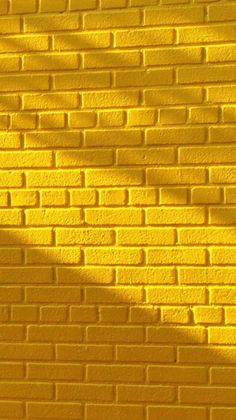 a yellow brick wall is shown with the shadow of a tree on it's side