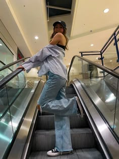 a woman standing on an escalator with her hands in her pockets and looking at the camera