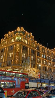 a double decker bus parked in front of a building with christmas lights on it's sides