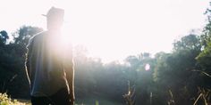 a man is standing in the grass with his back to the camera and looking into the distance