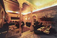 people are sitting at tables in an old building with stone walls and beams on the ceiling