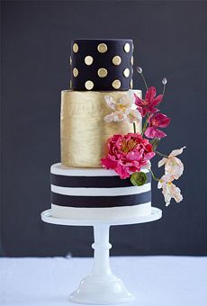 a three tiered cake with black and white stripes, gold polka dots and pink flowers