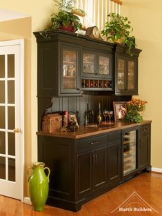 a kitchen with black cabinets and green vases on the counter top in front of it