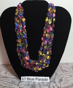 a necklace with multicolored glass beads on a black mannequin head stand