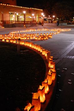 many lit up paper bags are lined up on the ground in front of a building