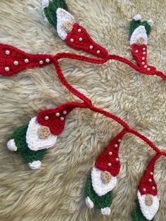 crocheted christmas garlands with santa hats and bells hanging on a furry surface