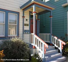 a blue house with red trim and white steps leading up to the front door on a sunny day