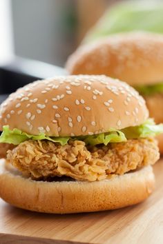 two sesame seed chicken sandwiches on a cutting board