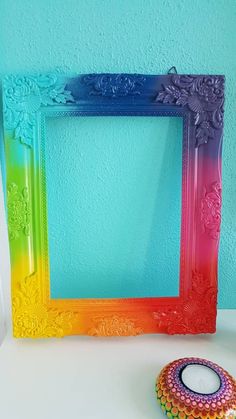 a rainbow colored frame sitting on top of a table next to a small candle holder