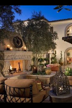 an outdoor living area with couches, tables and fireplace in front of a house