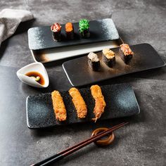 sushi and chopsticks sit on black plates with chop sticks next to them