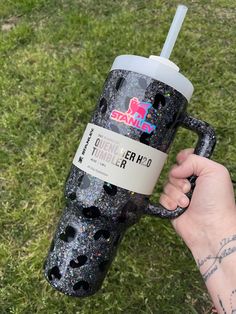 a person holding up a black and silver glittered cup with a straw in it