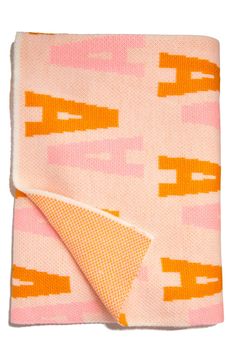 an orange and pink blanket folded on top of a white surface with the word love written across it