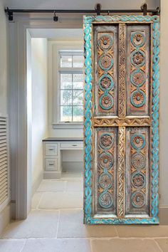 an old wooden door with blue paint on it in a hallway next to a window