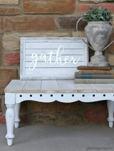 a white bench sitting next to a brick wall with a sign that says gather on it