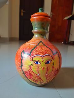 an orange and green vase sitting on top of a white floor