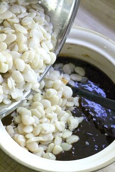 the bowl is full of rice and beans with a ladle pouring it into it