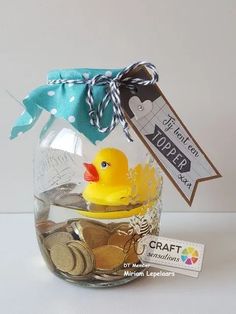 a glass jar filled with coins and a rubber ducky on the top, next to a tag that says craft creations