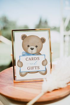 a teddy bear holding a card with the words cards and gifts on it